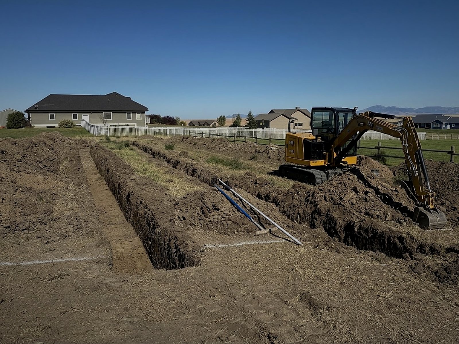Highland Construction excavator digging drain field trenches for a septic system